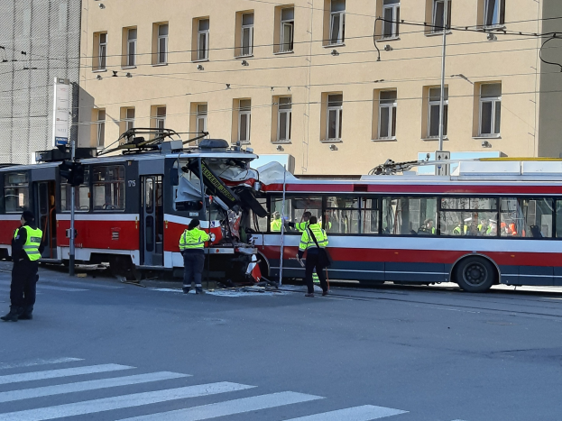 Rote und weiße Straßenbahn war in einen Straßenrandunfall mit mehreren Menschen in der Nähe und einem Gebäude im Hintergrund verwickelt.