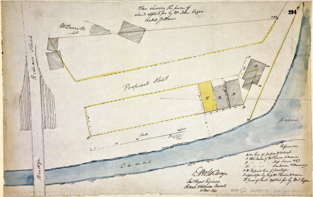 Eine detaillierte handgezeichnete Karte eines vorgeschlagenen Standorts auf Papier, einschließlich Straßen, Gebäuden und Landmarken, begleitet von erklärendem Text.
