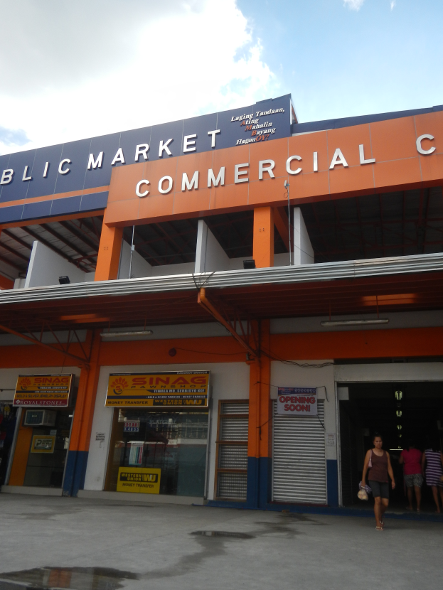 Ein öffentlicher Markt mit Menschen davor, Text auf dem Gebäude und sichtbarem Himmel oben.