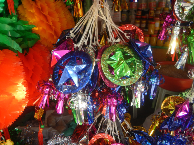 Bunte Dekorationen wie Laternen und B├Âgen h├Ąngen von der Decke über Regalen mit Flaschen in einer festlichen Atmosph├Ąre.