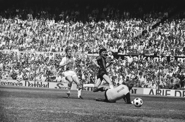 Schwarzes und weißes Foto von Fussballspielern im Einsatz auf einem Feld mit Zuschauern im Hintergrund und einer Bundesliga 1978-79 Ajax gegen Hannover 96-Tafel.
