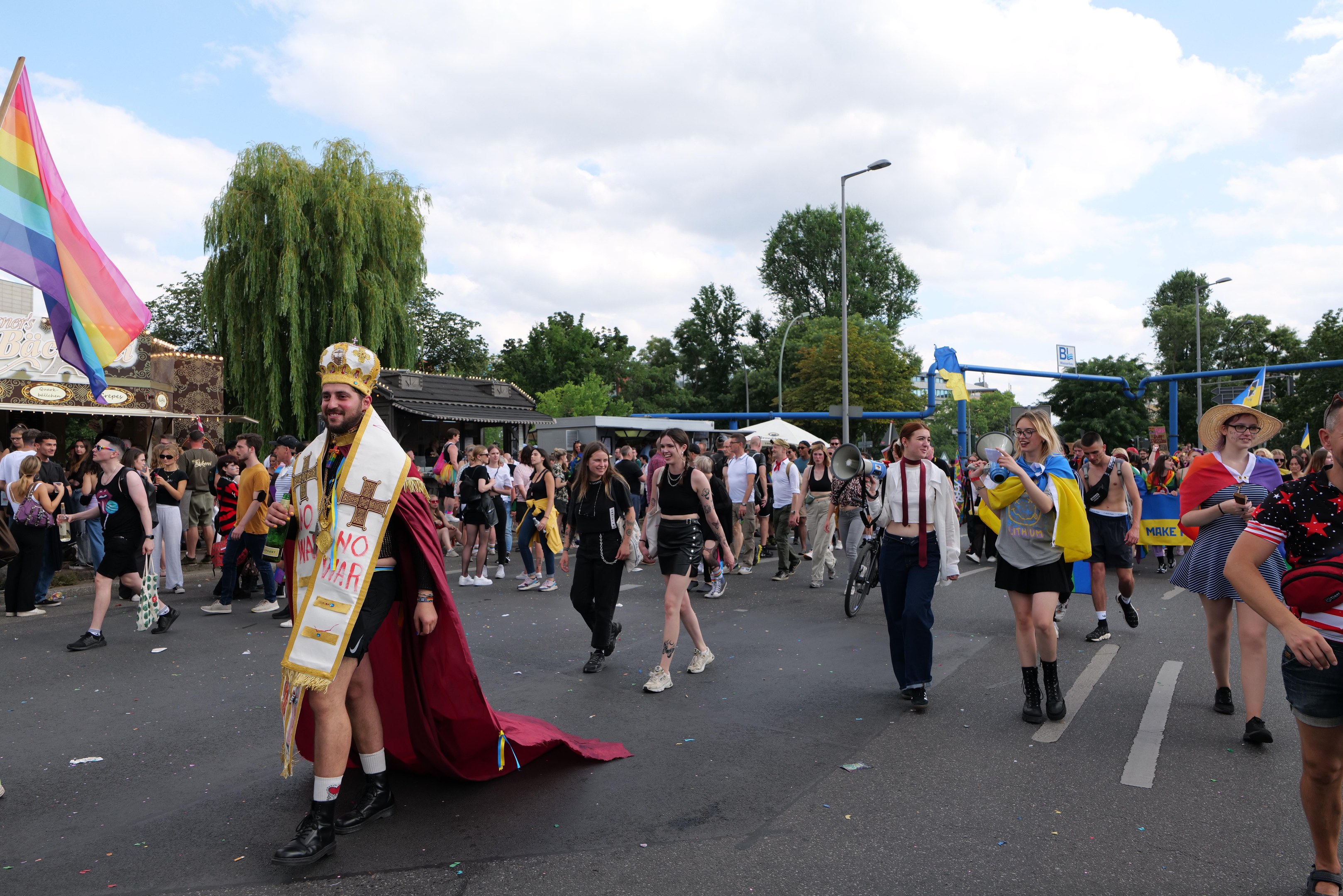 Eine Gruppe von Menschen, die bei der Gay Pride Parade 2018 marschieren und eine Regenbogenflagge sowie Musikinstrumente tragen.
