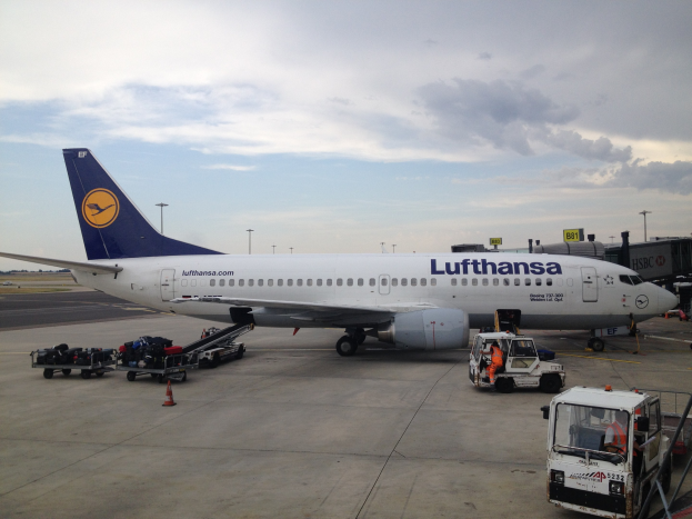 Lufthansa Airbus A320-200 auf dem Frankfurt Airport mit Bodenfahrzeugen, Verkehrszeichen und Informationsschildern unter einem bewölkten Himmel.