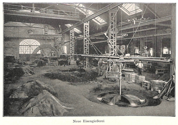 Schwarzes und weißes Foto einer deutschen Fabrik des 19. Jahrhunderts mit Arbeitern, die Maschinen bedienen, umgeben von Metallstangen und -pfählen, beschriftet mit "Neue Eisenglebeerei, die erste Fabrik Deutschlands" unten.