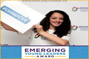 Eine Frau mit strahlendem Lächeln hält ein Schild hoch, auf dem "Emerging Young Leaders Award" steht, ihre Augen funkeln vor Freude und Stolz.