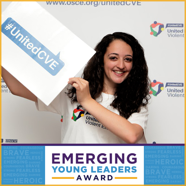Eine Frau mit strahlendem Lächeln hält ein Schild hoch, auf dem "Emerging Young Leaders Award" steht, ihre Augen funkeln vor Freude und Stolz.