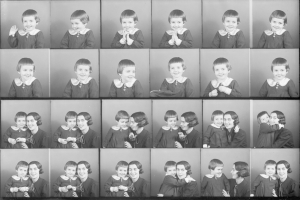 Schwarzes und weißes Foto einer Gruppe von Kindern mit einer Frau in der Mitte, die ein Baby hält und beide liebevolle Gesichter zeigen.