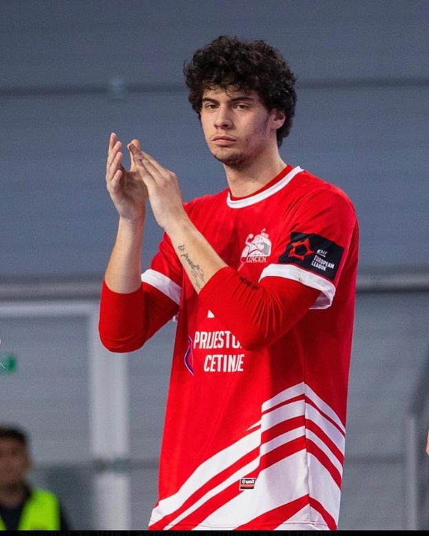 Ein Mann in rot-weißem Shirt, der in den Vordergrund klatscht, mit einer anderen Person und einer Wand im Hintergrund und Text unten lesend "Copenhagen Futsal Club - Foto 1"