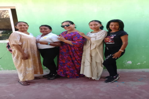 Gruppe von Frauen, die vor einer grünen Wand mit einem Fenster auf der linken Seite stehen und an einem Internationalen Frauentag-Event teilnehmen.