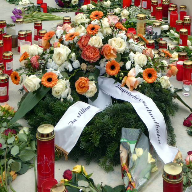 Mahnmal in Berlin, Deutschland, mit Blumen und Kerzen vor einer Wand auf dem Boden.