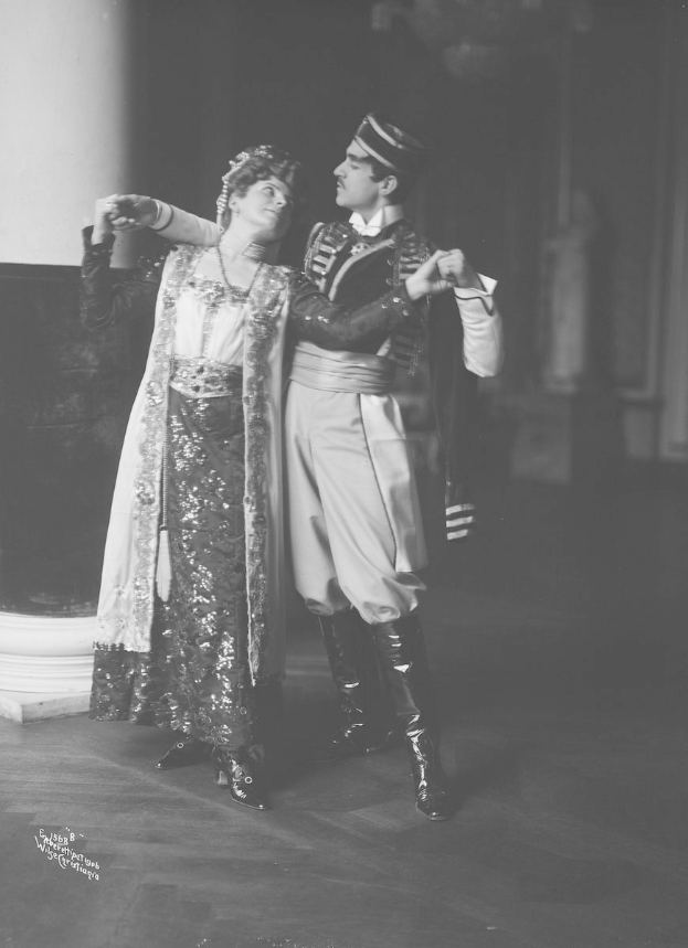 Schwarzes und weißes Foto eines Mannes und einer Frau, die in einem Ballsaal tanzen, mit einer Säule und einer Wand im Hintergrund.