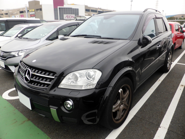 Schwarzer Mercedes-Benz ML 350 CDI BlueEfficiency auf einem Parkplatz mit Gebäuden, Masten und Bäumen unter einem klaren blauen Himmel geparkt.