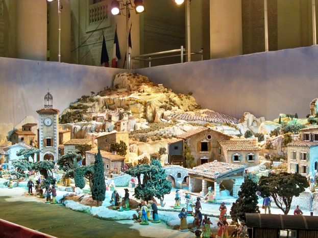 Eine detaillierte Museumsausstellung eines Krippenmodells mit Figuren, Strukturen und beleuchteten Elementen.