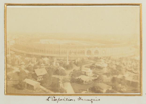 Altes Schwarz-Weiß-Foto eines Stadions, umgeben von Gebäuden, Bäumen und Strommasten mit Text am unteren Rand.