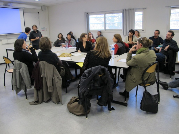 Eine Gruppe von Menschen, die sich unterhalten und diskutieren, mit zwei anderen, die separat stehen und sprechen.